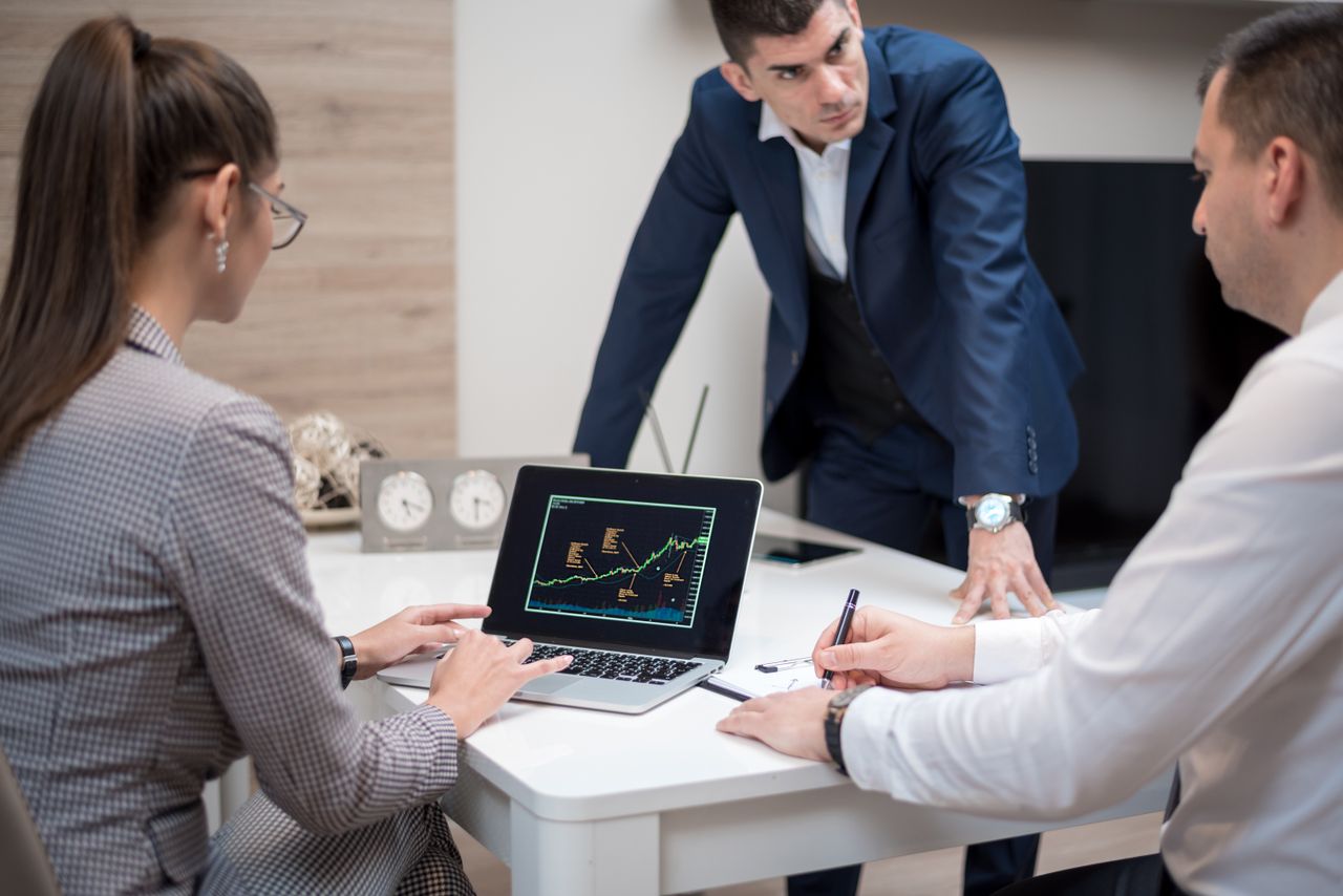 Professional team analyzing stock market trends on a laptop during a meeting.